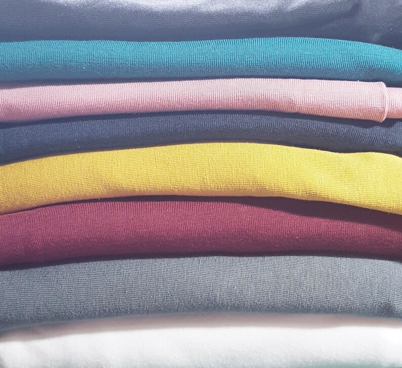 May include: A stack of folded fabric in various colors, including teal, pink, black, yellow, burgundy, gray, and white.
