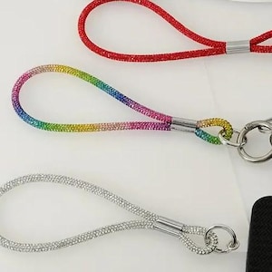May include: Three different keychains with rhinestones. The first keychain is red, the second is rainbow, and the third is silver.