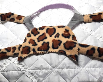 Può includere: Un cinturino per la testa in tessuto con stampa leopardata marrone e beige per una macchina CPAP. Il cinturino ha una cinghia regolabile grigia e viola sul retro.