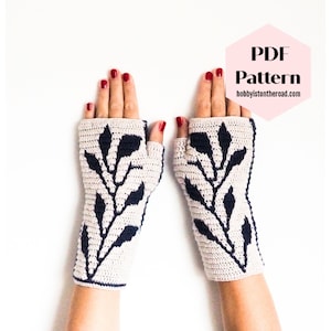 Könnte beinhalten: Ein Paar fingerlose Häkelhandschuhe mit einem Blattmotiv in Marineblau und Beige. Die Handschuhe werden an einem Paar Händen mit rotem Nagellack gezeigt. Der Text "PDF Pattern hobbyistontheroad.com" befindet sich in der oberen rechten Ecke des Bildes.