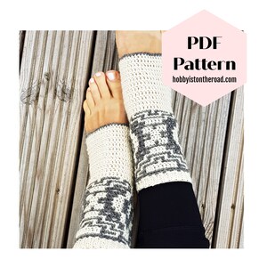 Puede incluir: Calentadores de piernas de ganchillo color crema con un patrón geométrico gris. Los calentadores de piernas se muestran en las piernas de una persona, con los pies visibles. El texto "PDF Pattern" y la dirección del sitio web "hobbyisontheroad.com" también son visibles.