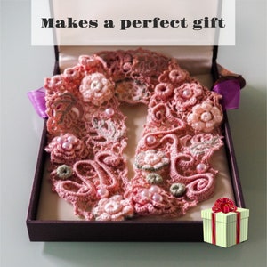 K&ouml;nnte beinhalten: Ein zartes, rosafarbenes H&auml;kelspitzen-Kragen mit Perlen-Akzenten, pr&auml;sentiert in einer Geschenkbox mit einer rot-wei&szlig; gestreiften Geschenkbox mit einer roten Schleife oben. Macht ein perfektes Geschenk.