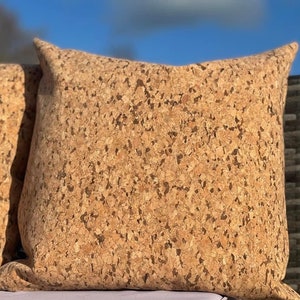 May include: A close-up of a brown cork pillow with a textured surface. The pillow is made of natural cork and has a soft, comfortable feel.