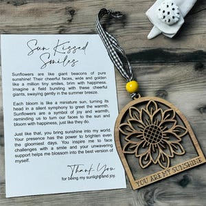 May include: Wooden sunflower ornament with the text "You are my sunshine" and a message about sunflowers being like beacons of sunshine and bringing joy. The text "Sun Kissed Smiles" and "Thank You for being my sunlight and joy" are also included.