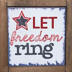 May include: A white wooden sign with a red, white, and blue star and the text "LET freedom ring".