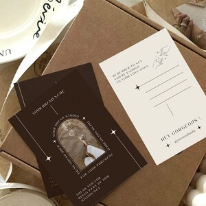 May include: A brown card with white text that says "Thank you so much for your purchase." and "Thank you for being part of our joyous day." The card also has a photo of a person's foot on a beach with a white archway above it. The card has a white border and stars on it.
