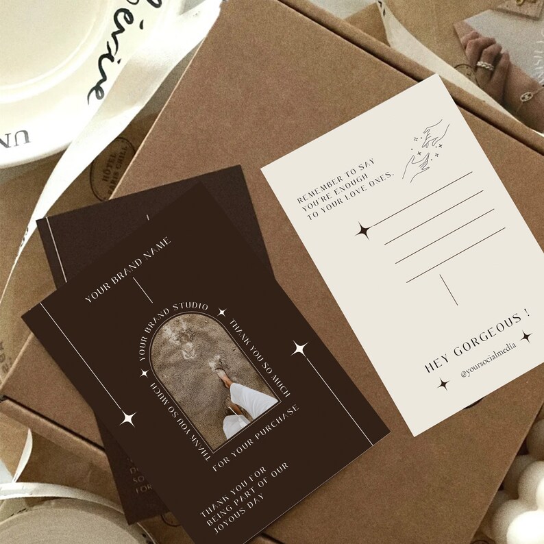May include: A brown card with white text that says "Thank you so much for your purchase." and "Thank you for being part of our joyous day." The card also has a photo of a person's foot on a beach with a white archway above it. The card has a white border and stars on it.
