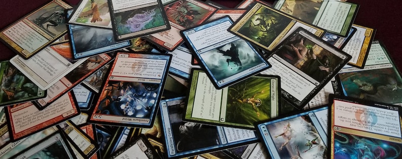 May include: A large pile of colorful trading cards featuring fantasy creatures and illustrations. The cards are arranged in a random order, with some cards overlapping others.
