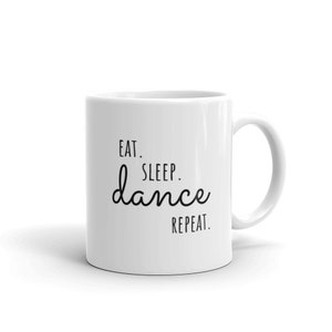May include: White ceramic coffee mug with black text that reads "Eat. Sleep. dance. Repeat."