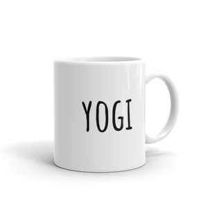 May include: White ceramic coffee mug with a black inscription that reads "YOGI".