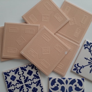 May include: A set of six beige ceramic tiles with a textured surface and the words "Made in Portugal" printed on them. There are also two white ceramic tiles with blue floral patterns.