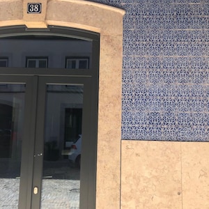 May include: A building with a black door and a tiled facade. The tiles are blue and white with a floral pattern. The door has a number "38" above it.
