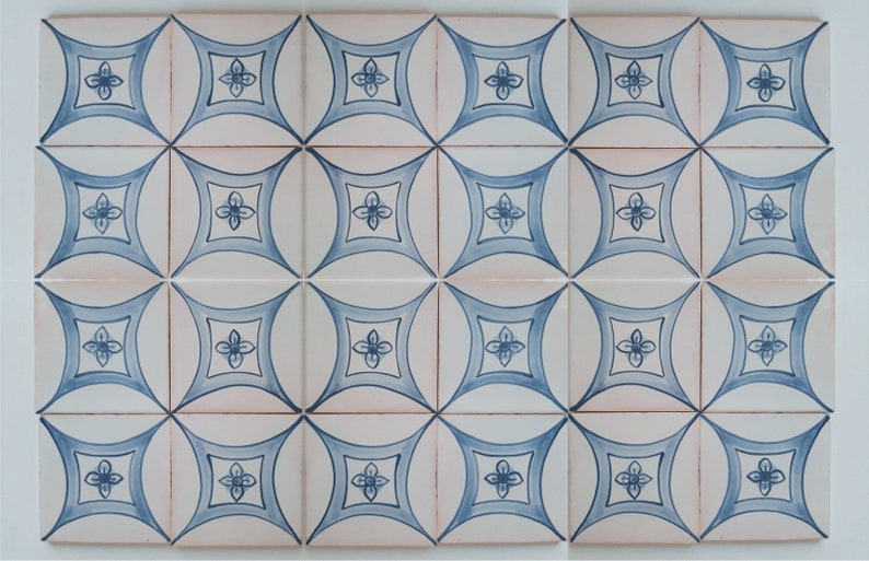 May include: A set of 24 white ceramic tiles with a blue floral pattern. The tiles are arranged in a grid pattern and have a slightly curved shape.