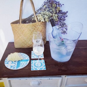 Peut inclure: Une table en bois avec un sac en osier, deux verres &agrave; vin, une bouteille de vin dans un seau &agrave; glace transparent et un dessous-de-verre en carrelage bleu et blanc.