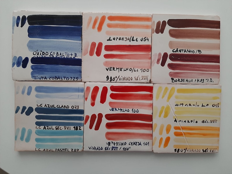 May include: Six ceramic tiles with color swatches of blue, red, orange, and brown paint. Each tile has a label with the name of the color and the paint number. The tiles are arranged in two rows of three.
