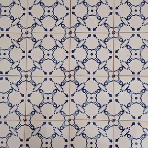 Puede incluir: Un suelo de baldosas blancas con un patrón geométrico azul y blanco que se repite. El patrón está formado por pequeños círculos y líneas.