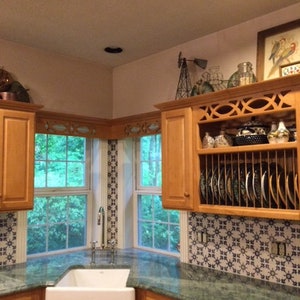 May include: A kitchen with a corner sink and green granite countertops. The cabinets are wood and have a decorative open shelf with a dish rack. The backsplash is blue and white patterned tile.