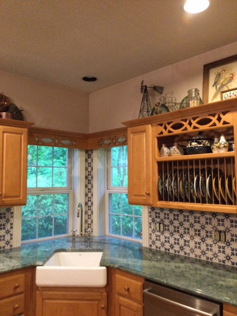 May include: A kitchen with a corner sink and green granite countertops. The cabinets are wood and have a decorative open shelf with a dish rack. The backsplash is blue and white patterned tile.