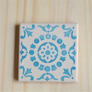 Peut inclure: Un carreau de c&eacute;ramique blanc avec un motif g&eacute;om&eacute;trique bleu et blanc. Le motif pr&eacute;sente un motif floral central entour&eacute; de petits cercles et &eacute;toiles.