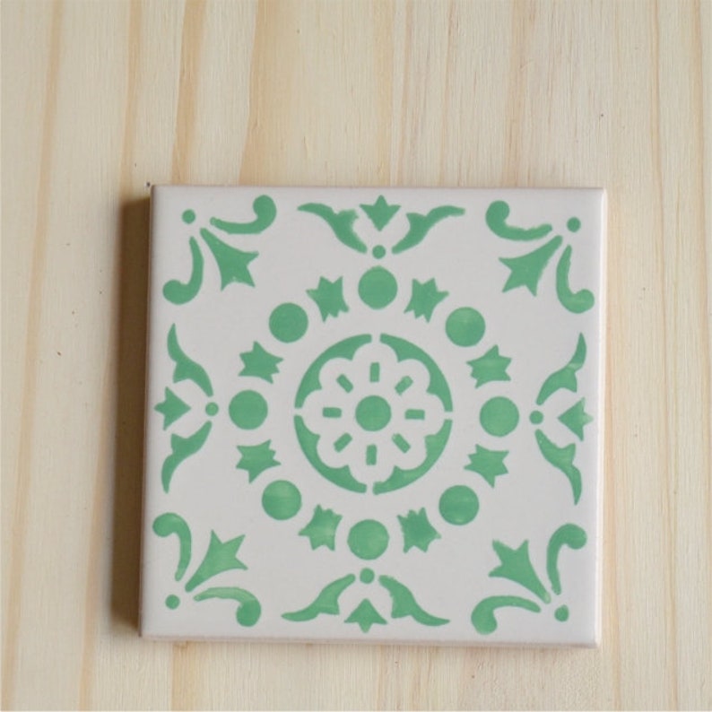 Peut inclure: Un carreau de c&eacute;ramique blanc avec un motif g&eacute;om&eacute;trique vert. Le motif pr&eacute;sente un motif floral central entour&eacute; de cercles, d'&eacute;toiles et de volutes.