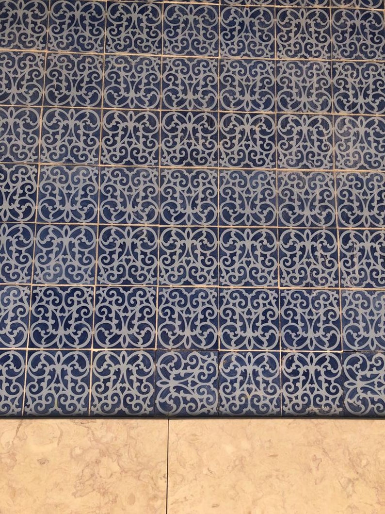 May include: A close-up of a tiled floor with a repeating pattern of blue and white intricate designs. The tiles are arranged in a grid pattern, creating a symmetrical and visually appealing surface.