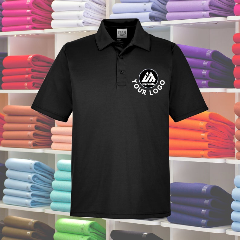 May include: Black polo shirt with a white logo on the left chest. The logo is a circle with a triangle inside and the text "ImprintMe" and "YOUR LOGO".