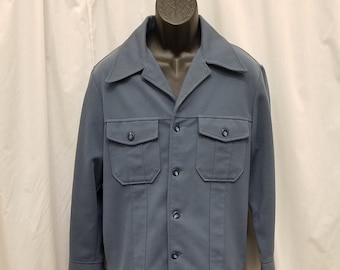 Puede incluir: Un traje azul con una chaqueta de manga larga y pantalones a juego. La chaqueta tiene un cierre de botones en la parte delantera y dos bolsillos grandes con solapa. Los pantalones tienen una pierna recta.
