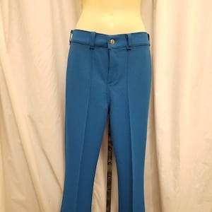 May include: A pair of blue trousers with a wide leg opening. The trousers have a zip and button fastening and are made from a textured fabric.