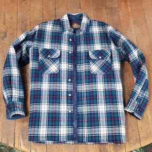 May include: A blue, white, and red plaid flannel shirt with long sleeves. The shirt has two chest pockets with button closures and a button-down front. The shirt is made of a soft, quilted material.