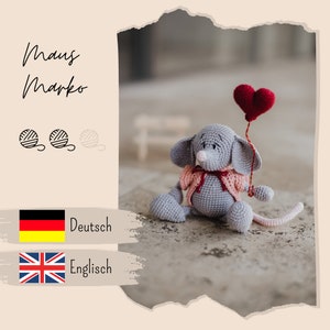 May include: A handmade gray crochet mouse toy with a pink bow and a red heart-shaped balloon. The mouse has large ears and a long tail. The image includes the text "Maus Marko" and yarn ball icons.