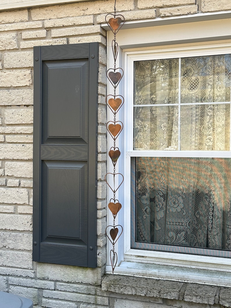 May include: A vertical hanging decoration consisting of a series of interconnected metal hearts. The chain features alternating solid copper-toned heart shapes and open wire heart outlines, suspended by a thin metal hook at the top.