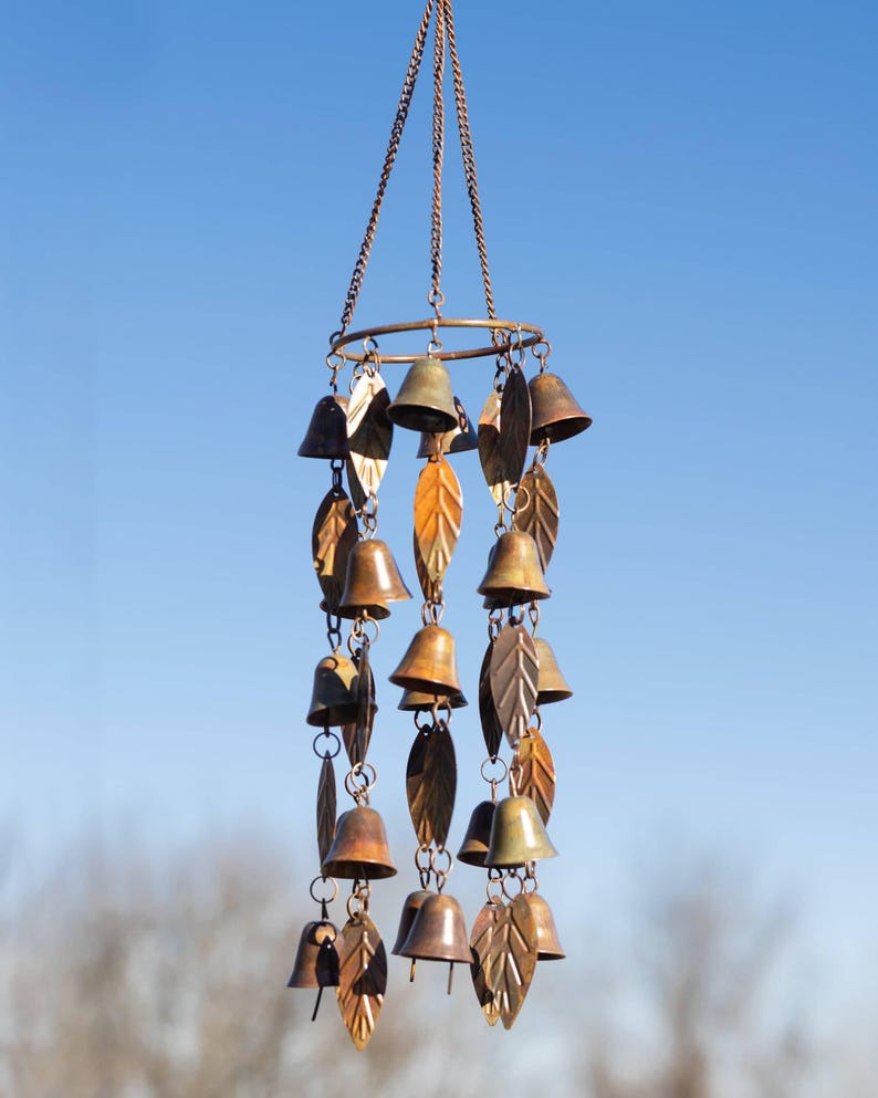 Single tiered metal wind chime with rustic copper finish featuring decorative hanging bells and leaf accents displayed in an outdoor garden setting. Handcrafted wind chimes outdoor for porch, patio, backyard, balcony, and garden decor. Metal wind chime adds soothing sounds and elegant movement to outdoor spaces. Rustic copper wind chime makes a beautiful gardener gift, gifts for mom, housewarming gift, outdoor garden decor, metal garden art, and yard decoration for every season.