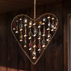 Handcrafted heart wind chime featuring colorful hanging dangles and decorative metal bells with a beautiful flamed finish. Metal wind chimes outdoor designed for garden decor, patio accents, porch decoration, balconies, fences, and backyard landscapes. Heart-shaped hanging garden ornament creates gentle, relaxing sounds while adding artistic charm to outdoor spaces. Perfect farmhouse decor, metal garden art, yard art, housewarming gift, romantic garden decor, and year-round outdoor decoration.