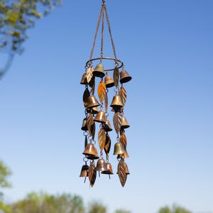 Single tiered metal wind chime with rustic copper finish featuring decorative hanging bells and leaf accents displayed in an outdoor garden setting. Handcrafted wind chimes outdoor for porch, patio, backyard, balcony, and garden decor. Metal wind chime adds soothing sounds and elegant movement to outdoor spaces. Rustic copper wind chime makes a beautiful gardener gift, gifts for mom, housewarming gift, outdoor garden decor, metal garden art, and yard decoration for every season.