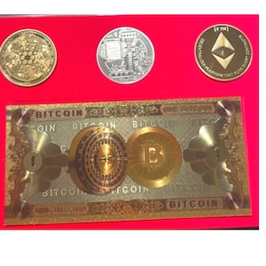 May include: A gold-colored paper bill with the word "BITCOIN" printed on it. The bill features a gold-colored coin with the letter "B" in the center. The bill is surrounded by a red background.