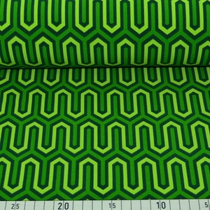 Op de afbeelding: Groene stof met een herhalend geometrisch patroon van in elkaar grijpende zeshoeken in groen- en donkergroentinten. De stof is dubbelgevouwen, wat de continuïteit van het patroon laat zien. Een liniaal met metrische maten staat onderaan.