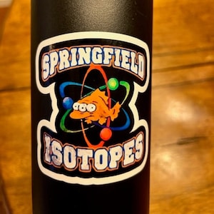 May include: Black water bottle with a white sticker featuring a cartoon fish with three eyes and the text "Springfield Isotopes".