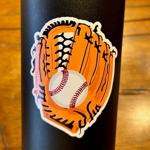 May include: A black water bottle with a sticker of an orange baseball glove catching a white baseball with red stitching.