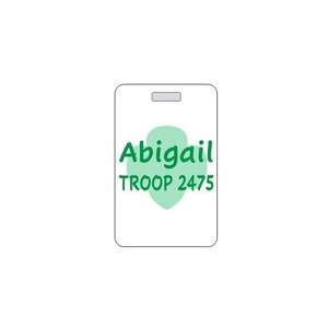 May include: White rectangular tag with a green four-leaf clover shape. The tag says "Abigail TROOP 2475" in green text.