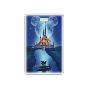 May include: A blue and white illustration of a castle with two moons in the shape of Mickey Mouse's ears. Mickey and Minnie Mouse are in a boat in front of the castle.