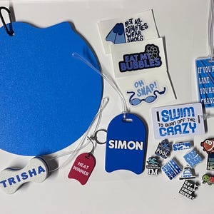 May include: A collection of swimming-themed accessories, including a large blue kickboard, luggage tags with names and phrases like "I Swim to Burn Off the Crazy," and various charms. The items are in shades of blue, white, and red.