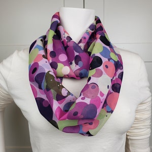 May include: A pink, green, and purple infinity scarf with a large, abstract polka dot pattern.