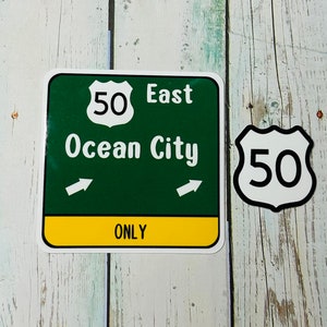 May include: Green and yellow road sign with white text that reads "50 East Ocean City ONLY".  There are two white arrows pointing to the right.  A white circle with a black border and the number "50" inside is in the upper left corner of the sign.  A white shield with a black border and the number "50" inside is to the right of the sign.