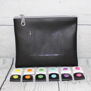 May include: Black zippered pouch with a clear plastic window. The pouch is surrounded by 12 colorful plastic clips with white backing.