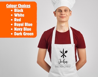 May include: A white chef hat and a white apron featuring a black graphic of a crossed fork, knife, and spoon above the text John and HEAD CHEF. An orange box on the left lists colour choices: Black, White, Red, Royal Blue, Navy Blue, Dark Green.