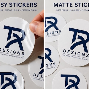 May include: Round white stickers with a dark blue logo featuring the letters TR and the text DESIGNS THE HOME OF PERSONALISATION. The left side shows glossy stickers with a smooth shine, while the right side shows matte stickers with no glare.