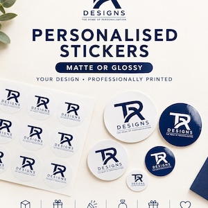 May include: A collection of circular stickers featuring the dark blue TR Designs logo. The display includes a sheet of white stickers, several loose white stickers, and two dark blue stickers of varying sizes, all professionally printed.
