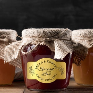 Peut inclure: Trois pots en verre avec des couvercles en toile de jute remplis de confiture. Le pot du milieu a une étiquette dorée avec le texte "Bella & Edward Spread the Love August 12th, 2021".
