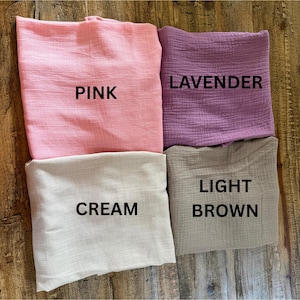 May include: Four folded pieces of textured fabric in pink, lavender, cream, and light brown. Each piece is labeled with black text: PINK, LAVENDER, CREAM, and LIGHT BROWN, indicating the specific color of each individual fabric square.
