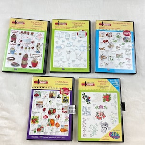 May include: Five DVD cases with embroidery designs. Titles include "For the Love of Chocolate," "Vintage Kitchen Linework," "Savory Herbs and Spices," "Fruit Delights," and "Borders for Linens." Each case features colorful graphics and design details.